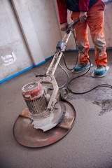 worker performing and polishing sand and cement screed floor