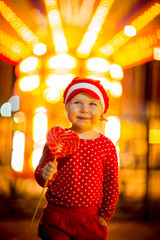 Little girl in red clothes and cap eats candy