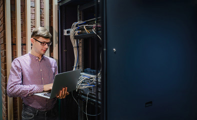 In the server room a technician/ It engineer/ hold the notebook