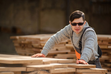 Portrait of young man carpenter at the wooden warehouse