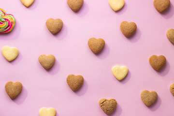 Flat lay composition with heart shaped cookies on pink paper background. Cookies pattern, minimal composition. Love concept. Romantic congratulation.