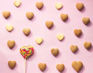 Flat lay composition with heart shaped cookies on pink paper background. Cookies pattern, minimal composition. Love concept. Romantic congratulation.