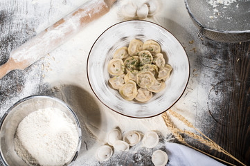 Russian traditional pelmeni with meat on a white plate. Wheat spikes, on a wooden board