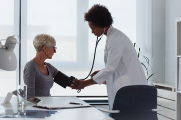 Female doctor checking blood pressure of a elderly woman at clinic