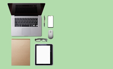 Office desk table with laptop, smart phone, cup of coffee and supplies, isolated on green background. Top view with copy space, flat lay.