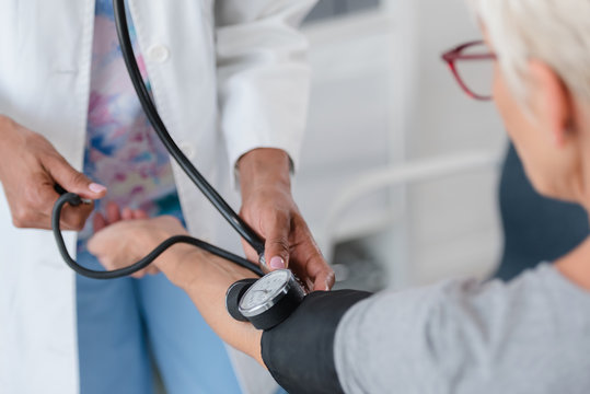 Female doctor checking blood pressure of a elderly woman at clinic