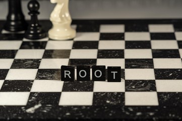 The concept of Root represented by black and white letter tiles on a marble chessboard with chess...