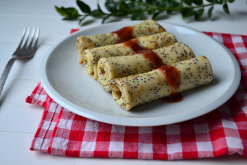 Traditional Russian and Ukrainian this pancakes with poppy seeds and strawberry jam on a white plate. National food for Maslenitsa.