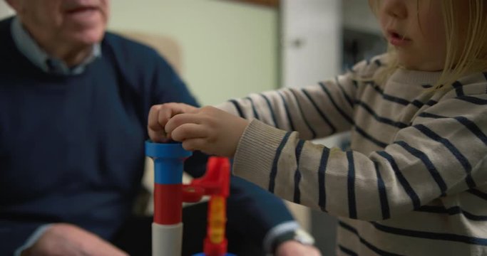 Little boy building a marble run with is grandfather