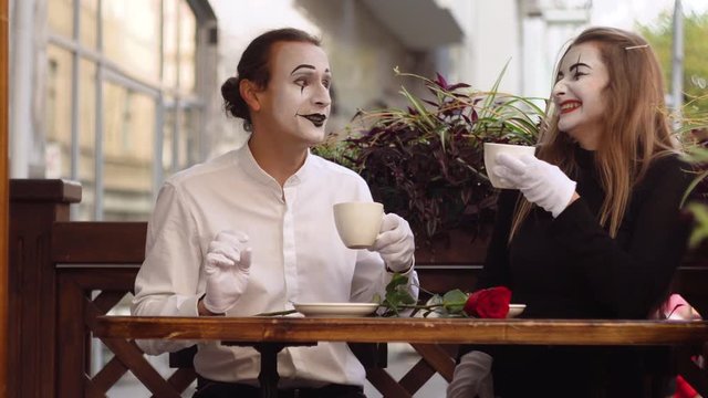 Two happy mime on a date drink coffee in the cafe. Romantic date