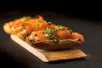 Whole toast with cheese spread and smoked salmon on wooden board