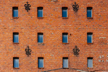 Obraz premium Fragment of an old red brick building and small windows.
