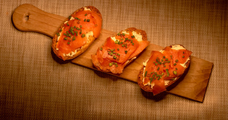 Whole toast with cheese spread and smoked salmon on wooden board