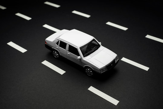 Upper view of a white car on a striped asphalt road