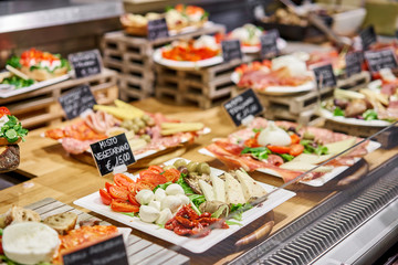 Various snacks and antipasti on the table of showcase. Street food market in Florence, Italy.