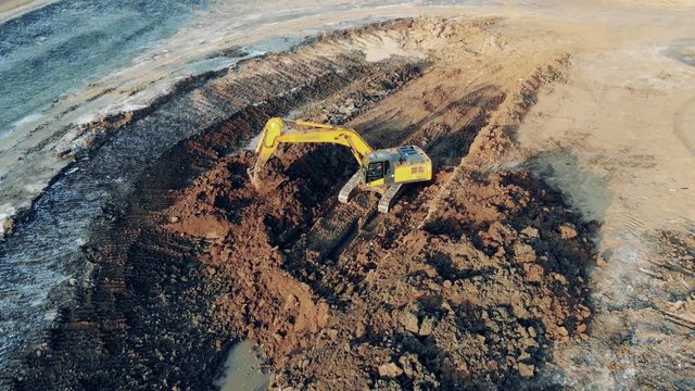 Borrow pit with and excavating machine digging ground