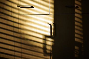 Sunlight through blinds onto old kitchen cupboards