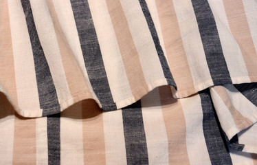 Obraz premium Beige and gray striped linen. Scandinavian style. The material is folded casually on a horizontal surface. Fabric sample. Interior design option for curtains