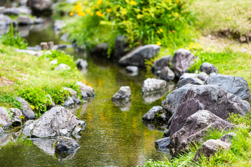 Fototapeta na wymiar Kyoto Gyoen Japan near Imperial Palace in Kyotogyoen with small creek river water surface and rocks during springtime closeup