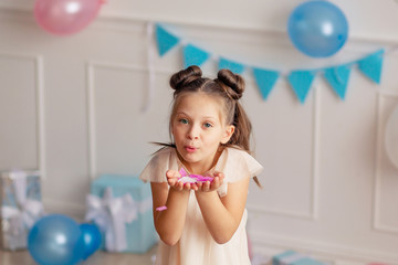 Happy Birthday. Portrait of a happy cute blond girl of 7-8 years old in a festive decor with confetti.