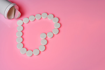 Medicines for the heart lie on a pink background. Heart pills and a bottle lie on a bright background.