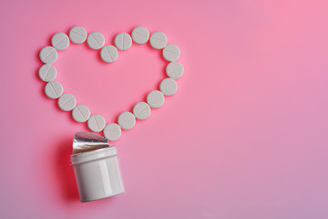 Bottle with medicines and pills in the form of a heart lie on a pink background. Pills. Medicine and healthy concept.