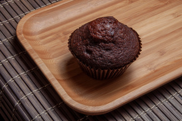 Dark chocolate muffin on wooden dish