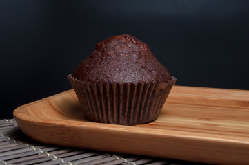 Dark chocolate muffin on wooden dish