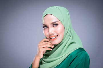 Headshot portrait of a beautiful female Muslim model in modern kurung and hijab, an urban lifestyle apparel for Muslim women isolated on grey background. Beauty and hijab fashion concept.