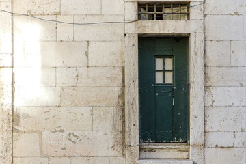 Old green door with a window on the old stone wall