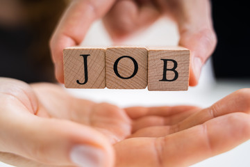 Person Giving Wooden Block With Job Text To Candidate