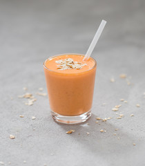 Carrot smoothie with oatmeal in a glass on a light background
