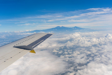 Obraz premium View from the airplane window of the Kilimanjaro volcano in the white clouds in Tanzania, Africa
