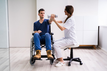 Therapist Assisting Disabled Patient While Doing Exercise
