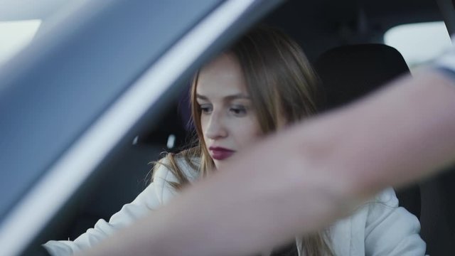 Woman in a car nods a head from someone's explaining auto mechanics