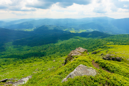 view in to the valley from the top of a mountain. huge rocks on the grassy hillside. clouds on the sky. beautiful sunny weather with dappled light. freedom in tourism concept