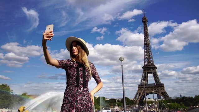 Millennial young girl taking selfie picture of Eiffel Tower on smartphone camera. Famous tourism & honeymoon landmark in Paris. 