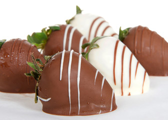 Close up on giant strawberries dipped in white and milk chocolate, drizzled with contrasting white and milk chocolate.