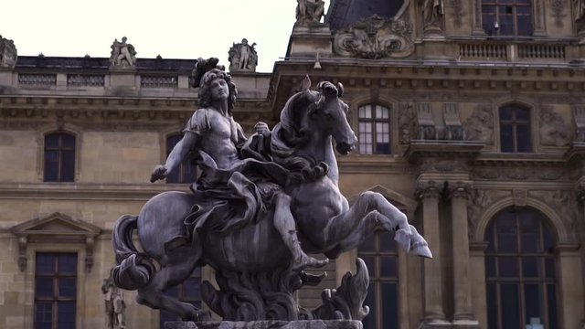 Statue in front of Louvre Museum building. Famous tourism  landmark in Paris. Slow motion glide. 