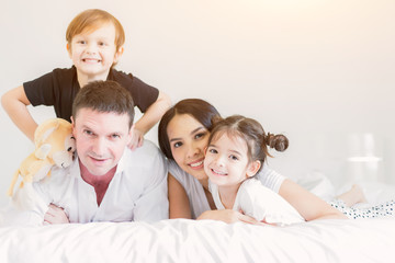 Happy family on holiday Parents and children tease each other on the bed.