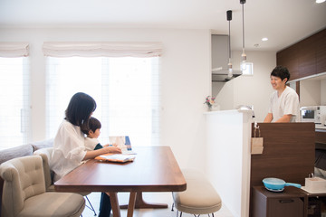 Obraz premium 家事をする父親と子供に本の読み聞かせをする母親