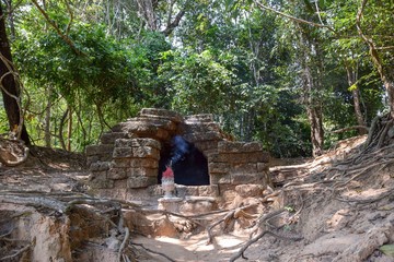 old grave, worship site hidden in the jungle, incense burning to dark cave enttance, angkor wat