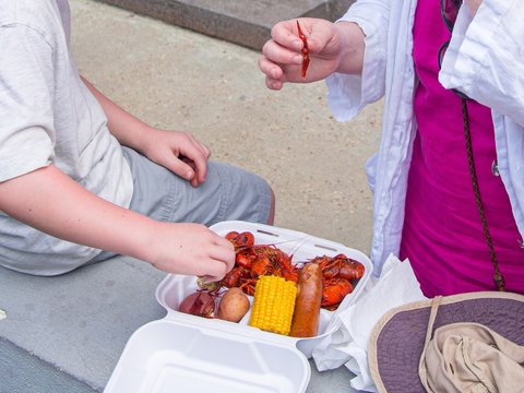 Child And Adult Eating Crawfish At The French Quarter Festival In New Orleans, LA, USA