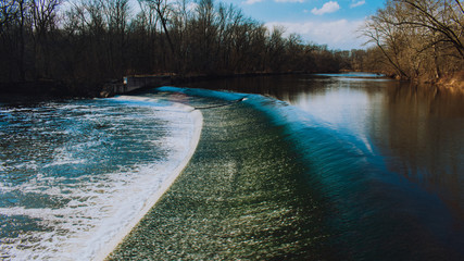 A Fast Flowing Waterfall With Deep Blue Water and White Foam With Trees in the Background