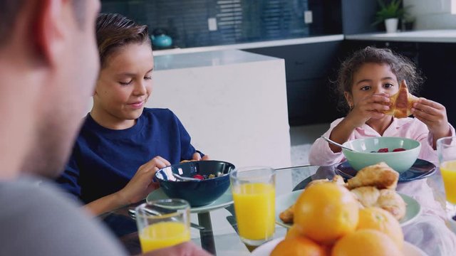 Hispanic Father With Children Sitting Around Table Eating Breakfast Together