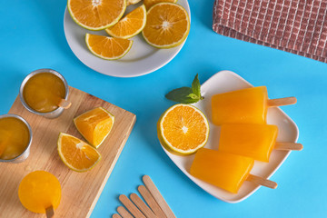 Orange popsicles with peppermint on white ceramic cup