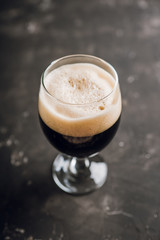 Freshly brewed dark beer on the black rustic background. Selective focus. Shallow depth of field.