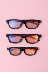 3D plastic glasses on a pink background, vertical photo