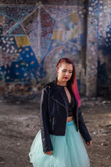 Naklejka premium Portrait of a young girl with pink hair standing inside of collapsed building surrounded by ruins