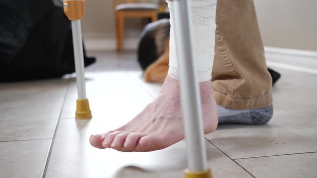 Man injured to his leg walking at home using crutches.